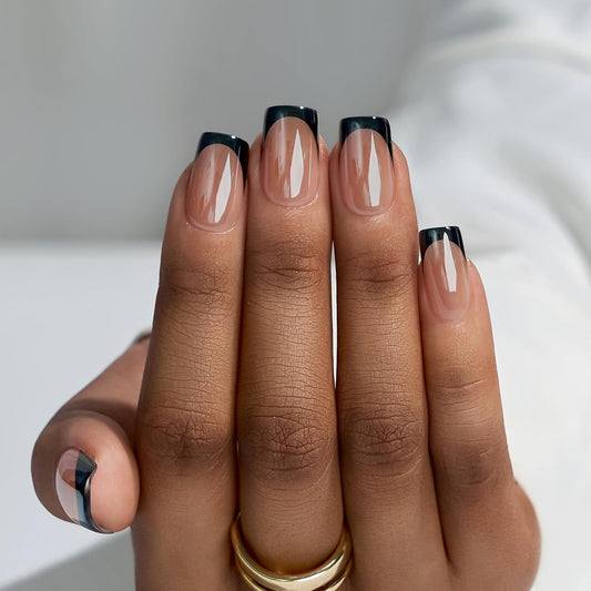 Hand with nails painted in a neutral color with black tips on a white background