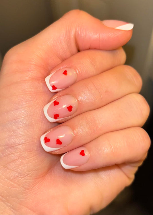 Hand with heart-shaped nail art on a neutral background