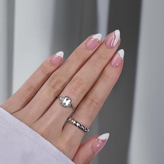Hand with pink and white nail polish wearing two silver rings on a neutral background